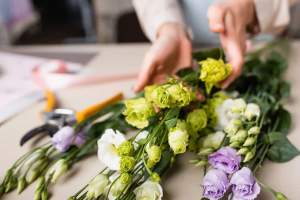 Vue partielle du bouquet fleuriste avec eustomie dans la boutique de fleurs sur fond flou — Photo de stock