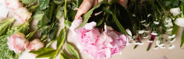 Vista cortada de florista com hortênsias florescentes perto de rosas e crisântemos na mesa, banner — Fotografia de Stock