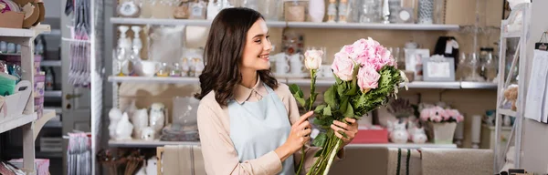 Fiorista femminile sorridente che organizza bouquet con rose, ortensie e crisantemi con rastrelliere di vasi su sfondo, banner — Foto stock