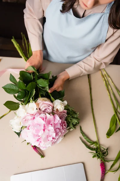 Vista cortada de florista feminino em avental compondo buquê na mesa com talos — Fotografia de Stock