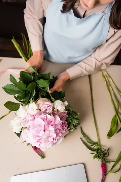 Vista ritagliata di fiorista donna in grembiule componendo bouquet sulla scrivania con steli — Foto stock