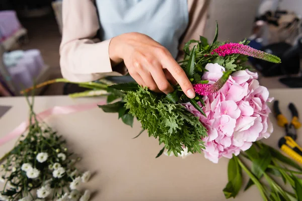 Vista cortada do florista feminino arranjando buquê com flores borradas no fundo — Fotografia de Stock