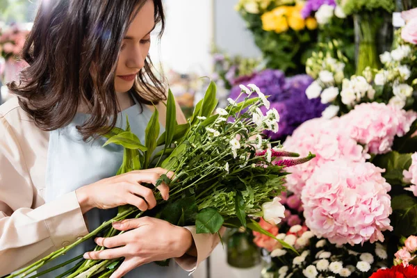 Feminino florista arranjar buquê com celosia nd crisântemos com flores borradas no fundo — Fotografia de Stock