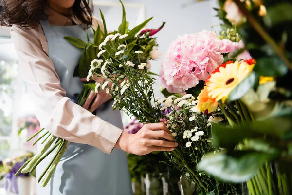 Vista ritagliata del fiorista che prende ramo di crisantemo, mentre raccoglie bouquet in negozio di fiori in primo piano sfocato — Foto stock