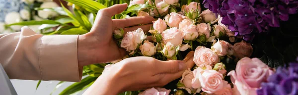 Ausgeschnittene Ansicht einer Floristin, die sich um Rosen in der Nähe von lila Hortensien kümmert, Banner — Stockfoto