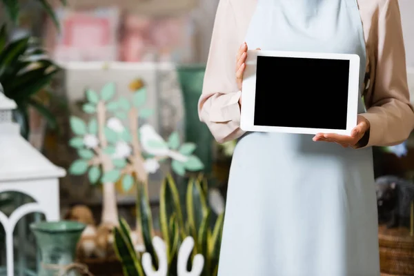 Vista recortada de florista femenina sosteniendo tableta digital con tienda de flores borrosas en el fondo - foto de stock