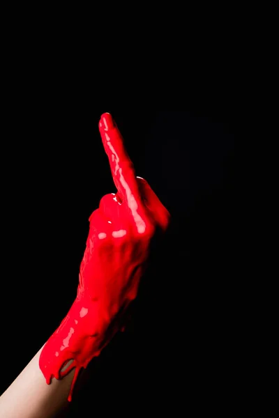 Cropped view of hand painted in red paint showing middle finger isolated on black — Stock Photo