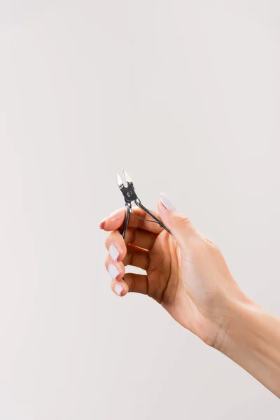 Cropped view of woman holding cuticle nipper isolated on grey — Stock Photo