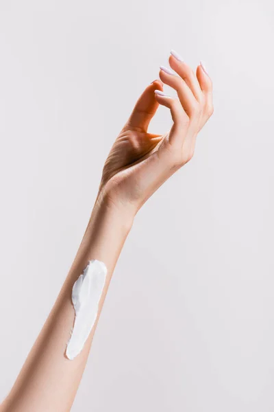 Vue recadrée de la femme avec crème pour les mains sur le bras isolé sur gris — Photo de stock