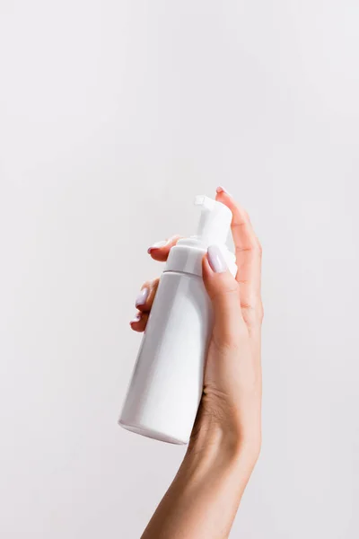 Cropped view of woman holding cleansing foam isolated on grey — Stock Photo