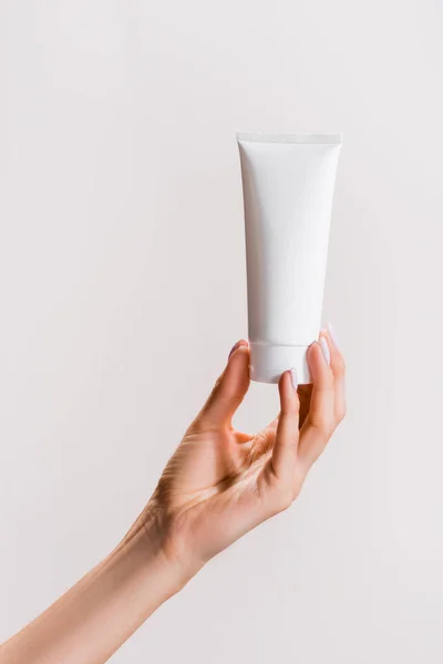 Vue recadrée de la femme tenant tube de crème pour les mains isolé sur gris — Photo de stock