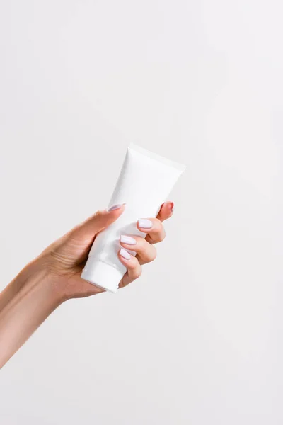 Vue recadrée de la femme tenant tube de crème pour les mains isolé sur gris — Photo de stock