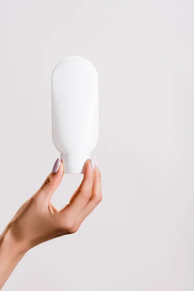 Cropped view of woman holding tube of hand lotion isolated on grey — Stock Photo