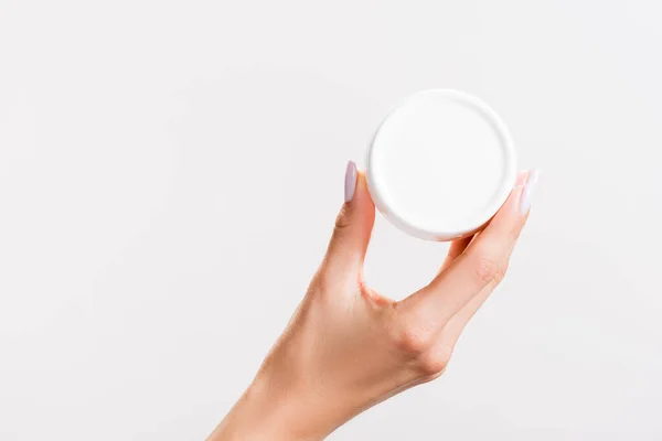 Vue recadrée de la femme tenant le récipient de crème pour les mains isolé sur gris — Photo de stock