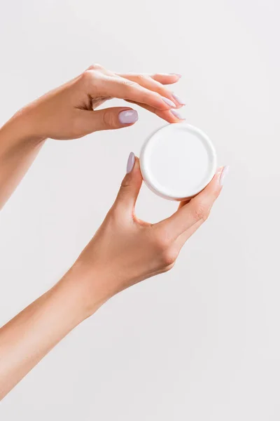 Cropped view of woman holding container of hand cream isolated on grey — Stock Photo