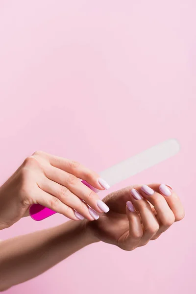 Vista recortada de la mujer usando lima de uñas aislado en rosa - foto de stock