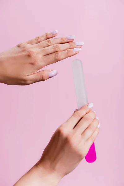 Vista ritagliata di donna in possesso di lima per unghie isolato su rosa — Foto stock
