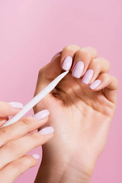 Vue recadrée de la femme en utilisant poussoir cuticule isolé sur rose — Photo de stock