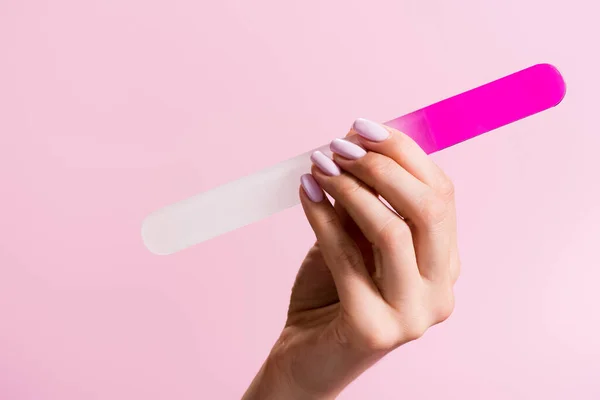 Vue recadrée de la femme tenant la lime à ongles isolée sur rose — Photo de stock