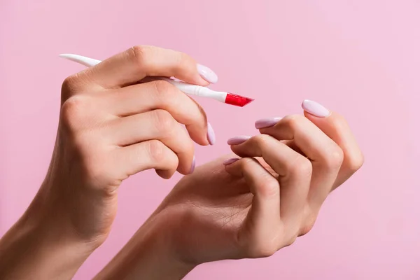 Cropped view of woman using cuticle pusher isolated on pink — Stock Photo