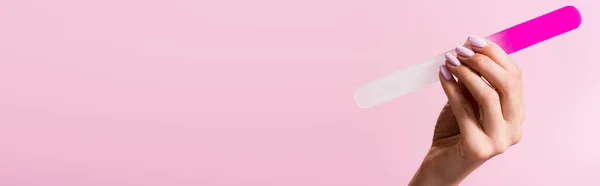 Vista cortada da mulher segurando arquivo de unhas isolado em rosa, banner — Fotografia de Stock