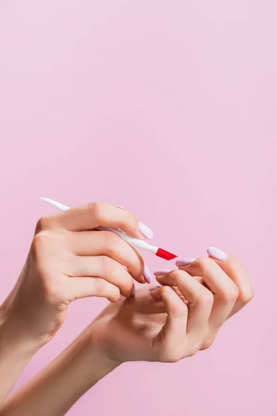 Cropped view of woman using cuticle pusher isolated on pink — Stock Photo