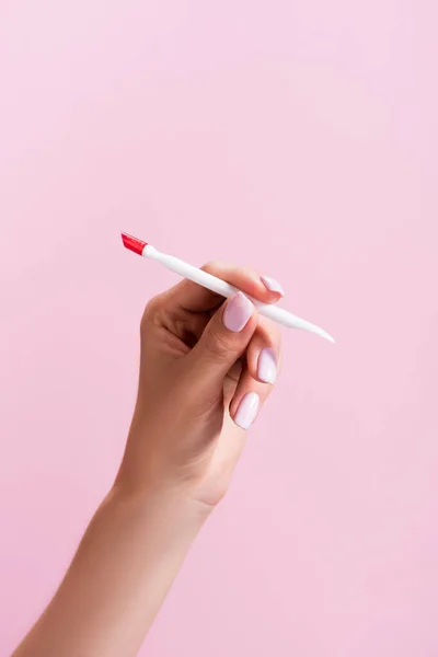 Cropped view of woman holding cuticle pusher isolated on pink — Stock Photo