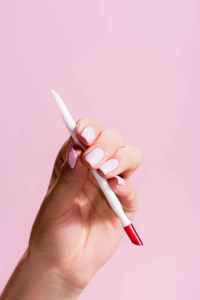 Cropped view of woman holding cuticle pusher isolated on pink — Stock Photo