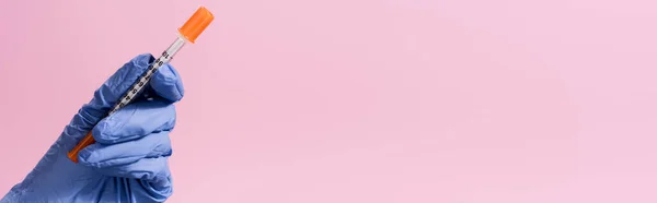 Обрізаний вид руки в латексній рукавичці з вакциною ізольовано на рожевому, банер — стокове фото