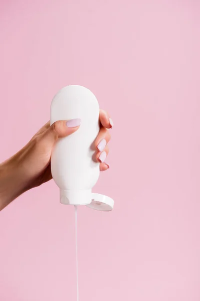 Cropped view of woman squeezing lotion isolated on pink — Stock Photo