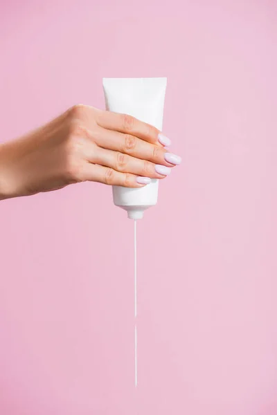 Vue recadrée de femme serrant crème pour les mains isolé sur rose — Photo de stock