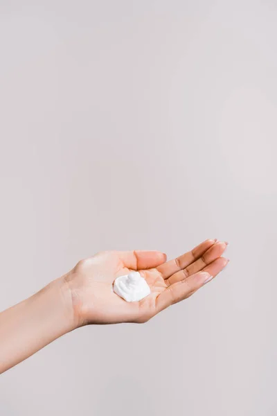Cropped view of woman showing hand cream isolated on grey — Stock Photo