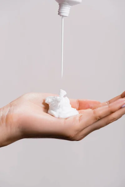 Cropped view of woman squeezing hand cream isolated on grey — Stock Photo