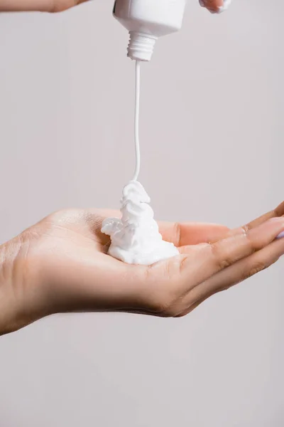 Vista recortada de la mujer apretando crema de manos aislado en gris - foto de stock