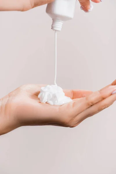 Cropped view of woman squeezing hand cream isolated on grey — Stock Photo