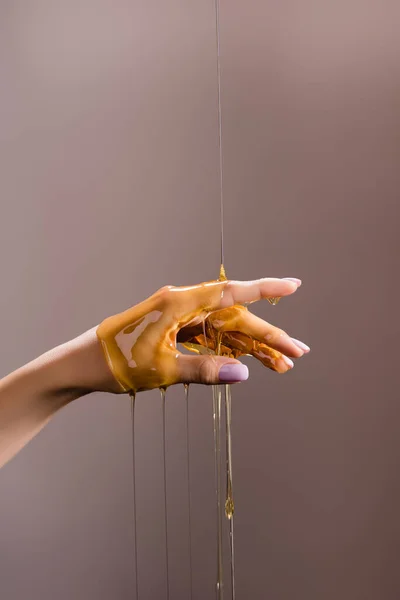 Cropped view of female hand in honey isolated on grey — Stock Photo