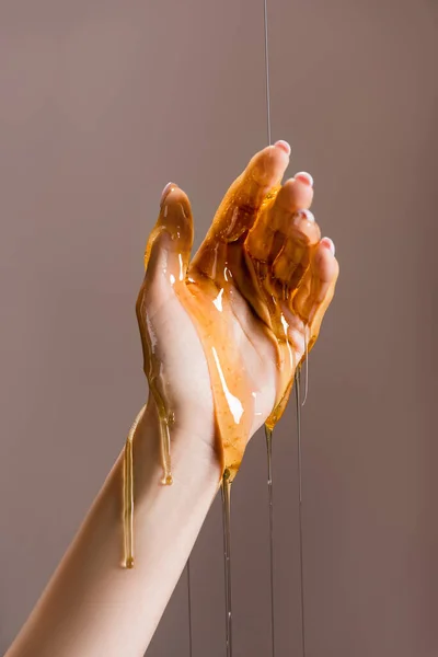 Cropped view of female hand in honey isolated on grey — Stock Photo