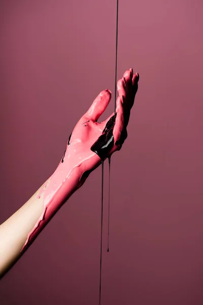 Visão parcial da mão com tinta gotejante isolada sobre rosa — Fotografia de Stock