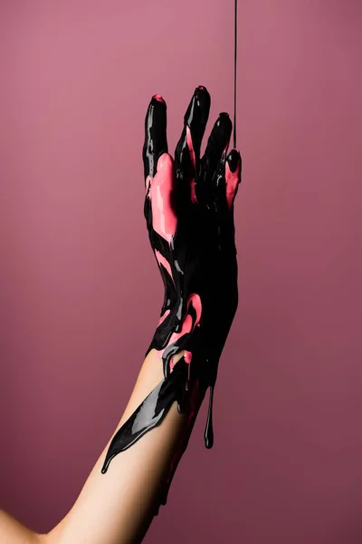 Partial view of hand with dripping black paint isolated on pink — Stock Photo