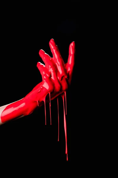 Vue partielle de la main peinte avec de la peinture rouge goutte à goutte isolée sur noir — Photo de stock