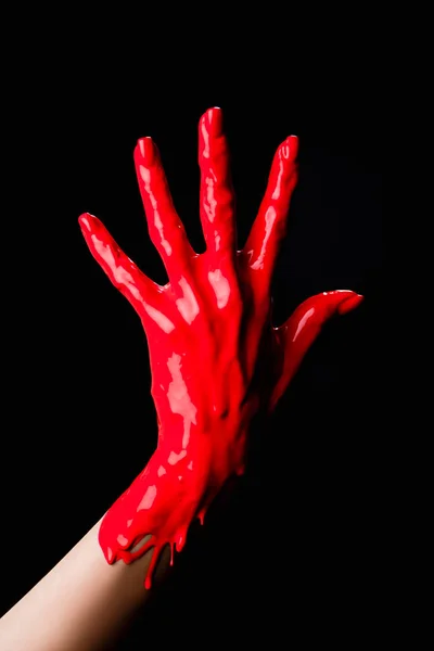 Partial view of painted hand with red dripping paint isolated on black — Stock Photo