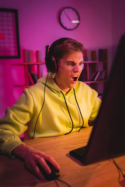 Aggressive gamer using computer on blurred foreground on table — Stock Photo