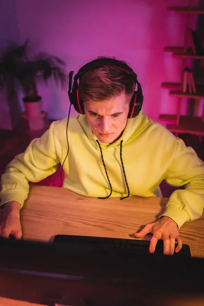 Гравець у навушниках, використовуючи комп'ютер на розмитому передньому плані — стокове фото