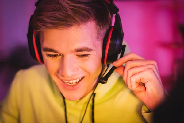 Cheerful gamer adjusting microphone of headset at home — Stock Photo