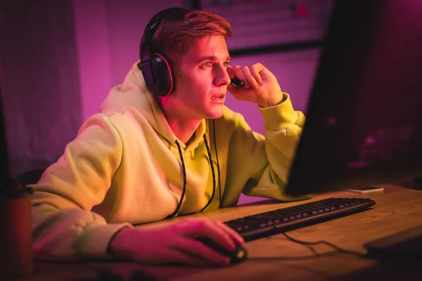 Joven con auriculares jugando a videojuegos cerca del café para ir en primer plano borroso - foto de stock