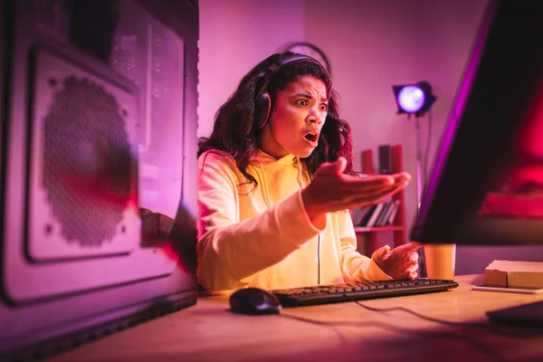 Jogador afro-americano chocado apontando com a mão para o computador durante o jogo de vídeo — Fotografia de Stock