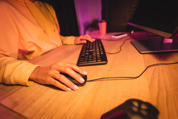 Cropped view of gamer using computer mouse while playing video game n blurred background — Stock Photo