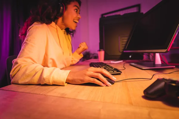 Alegre jugador afroamericano utilizando la computadora y mostrando sí gesto cerca de joystick en primer plano borrosa — Stock Photo