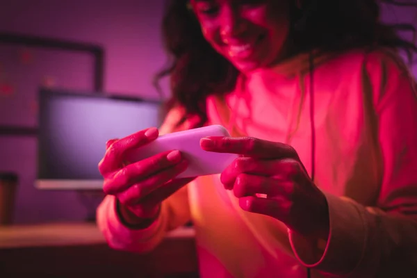 Smartphone in den Händen fröhlicher afrikanisch-amerikanischer Spieler auf verschwommenem Hintergrund — Stockfoto