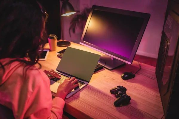 KYIV, UKRAINE - 21 de agosto de 2020: Gamepad perto do jogador afro-americano usando laptop em primeiro plano desfocado — Fotografia de Stock